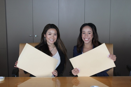 Two People holding papers smiling