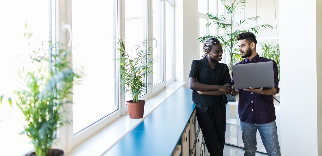 Two colleagues collaborating in an airy, plant-filled workspace