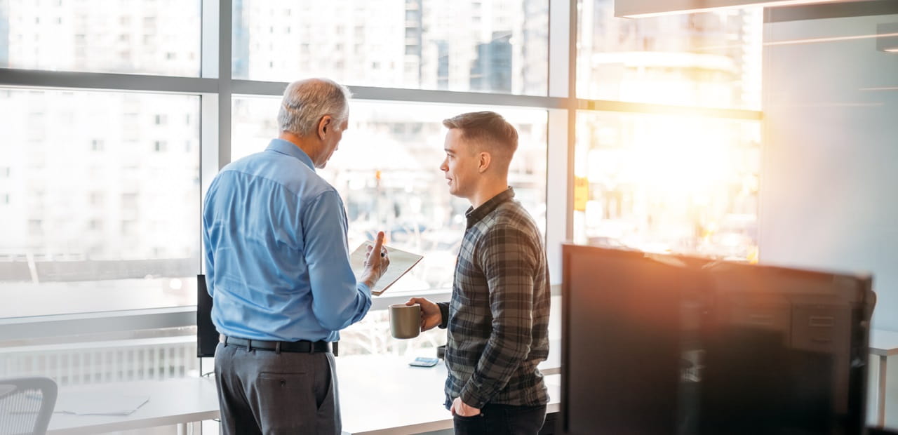 Two male coworkers talking in an office.