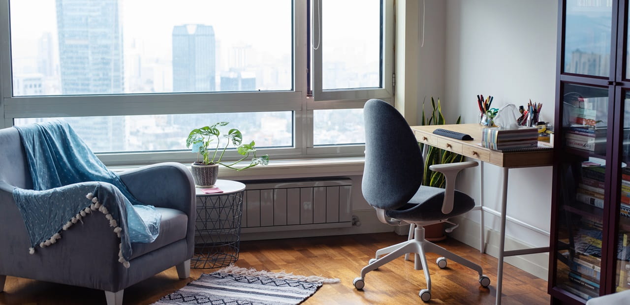 Workspace with a rolling chair and desk with a window view of a cityscape.