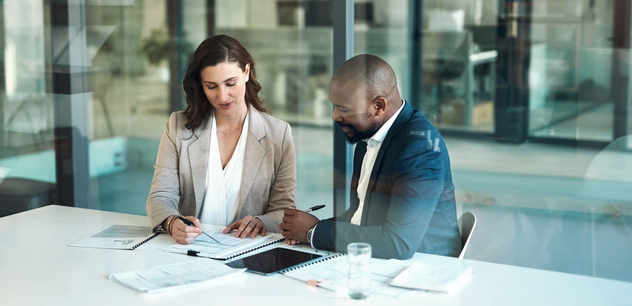 Business professionals sitting at a conference table reviewing documents.