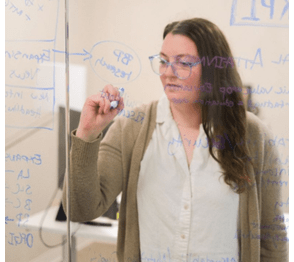 Employee from Slingshot brainstorms ideas on a glass board. 